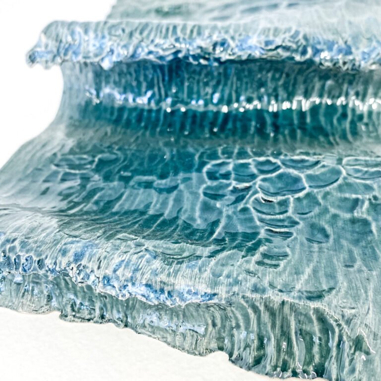 Wave in glazed ceramic. Sculpture created by Jaime Carvalho. Currently in the exhibition at Galeria Resistência in Lisbon. Inspired by the sea and wanting to represent its beauty and strength, Jaime developed a series of works in different materials, such as marble, wood, and metal, representing waves and the sea.