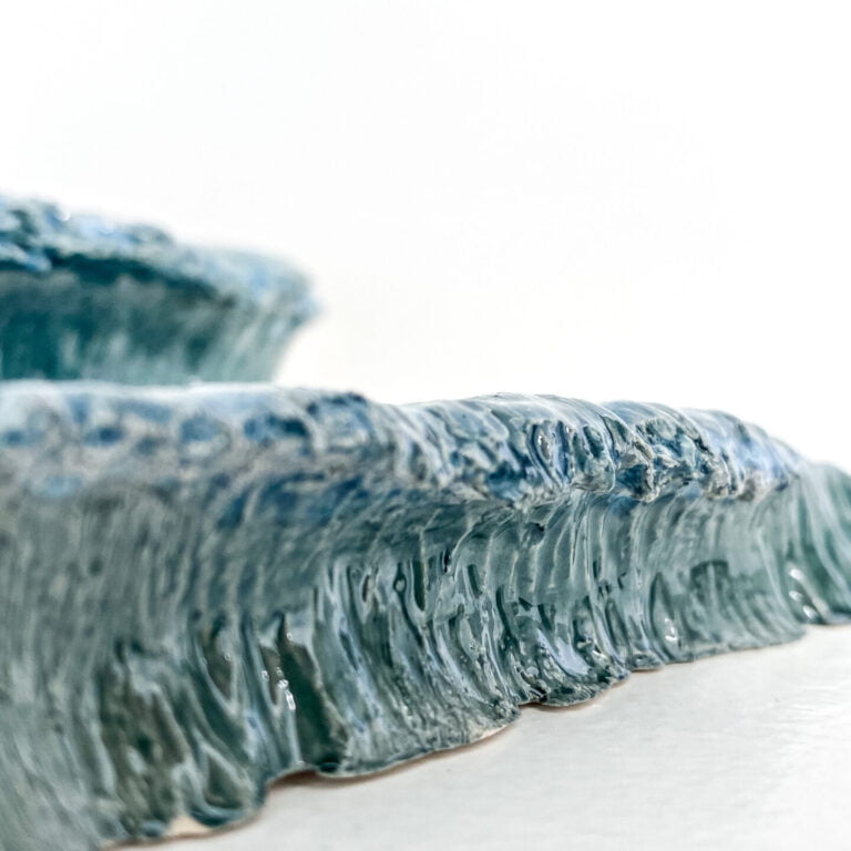 Wave in glazed ceramic. Sculpture created by Jaime Carvalho. Currently in the exhibition at Galeria Resistência in Lisbon. Inspired by the sea and wanting to represent its beauty and strength, Jaime developed a series of works in different materials, such as marble, wood, and metal, representing waves and the sea.
